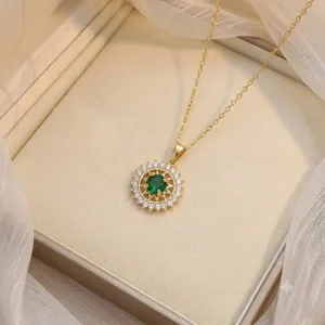 Detail view of gold sunburst pendant necklace with a brilliant green center stone.