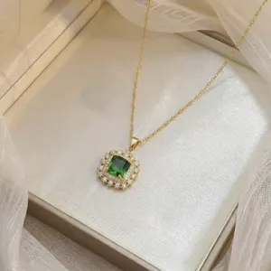 Close-up of square emerald green zircon pendant with white zircon halo on gold chain.