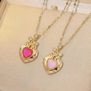 Close-up of two heart-shaped necklaces in gold with pink and magenta sparkly pendants.
