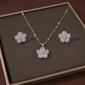 Elegante silberfarbene Halskette mit Blumenanhänger und passenden Ohrsteckern auf Tablett