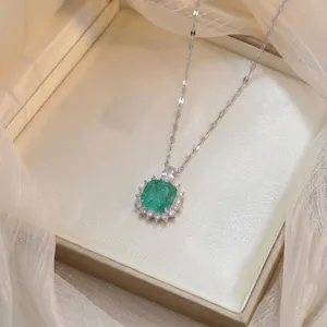 Détail d'un collier avec pendentif fleur en zircon vert émeraude sur boîte à bijoux.