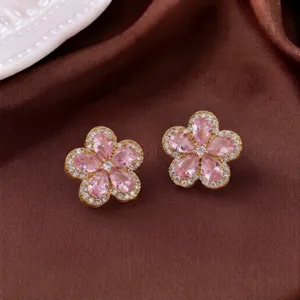 Elegante vergoldete Ohrstecker mit rosa Kristallblumen auf braunem Satinstoff