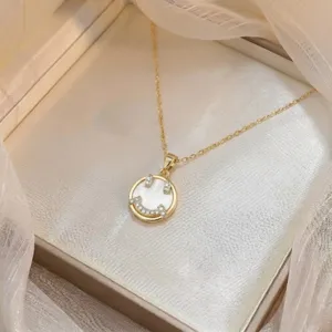 Nahaufnahme einer Goldkette mit einem Smiley-Anhänger, Zirkonia und Muscheleinlage