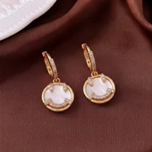 Nahaufnahme von goldenen Smiley-Ohrringen mit Perlmutt und Zirkonia-Verzierung