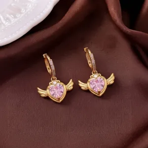 Nahaufnahme goldener Engelsflügel-Ohrringe mit herzförmigem rosa Zirkonia-Detail