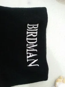 Λεπτομερής άποψη του λευκού κεντήματος BIRDMAN σε μαύρο χειμερινό πλεκτό σκούφο