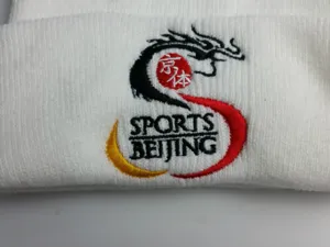 Κοντινό πλάνο με κέντημα δράκου και Sports Beijing σε λευκό πλεκτό σκούφο
