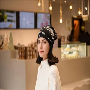Asian model wearing a stylish black cashmere-like slouchy beanie with cursive patterns.