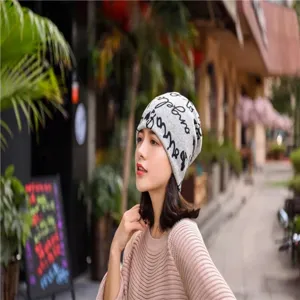 Close-up of a stylish grey slouchy beanie with black letter print on a model