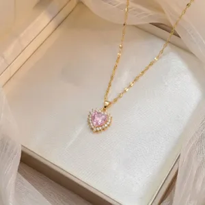 Primer plano de un elegante collar dorado con un colgante de circón rosa brillante en forma de corazón.