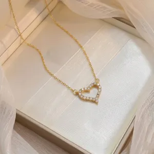 Primer plano de collar con colgante de corazón dorado brillante con circonitas en caja