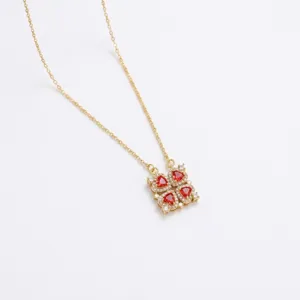 Primer plano detallado de un collar dorado con cuatro circonitas rojas en forma de corazón