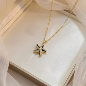 Vue détaillée d'un collier pendentif étoile de mer doré avec incrustations noires et zircons