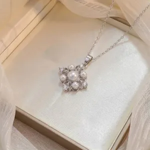 Macro view of a silver floral pendant with pearls and zircons on a satin box