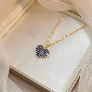 Primer plano de un elegante collar con colgante de corazón de oro y circón azul
