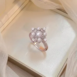 Detail of an elegant floral ring with central pearl and sparkling zircon stones