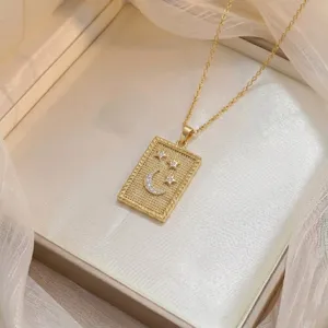 Gros plan d'un collier doré avec pendentif rectangulaire lune et étoiles en zircon