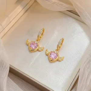Vue détaillée des boucles d'oreilles cœur en zircon rose avec ailes dorées en boîte
