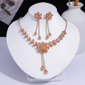 Parure collier et boucles d'oreilles fleur en zircon champagne présentée sur buste blanc