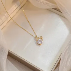 Détail d'un collier doré avec nœud papillon et pendentif en zircon étincelant.