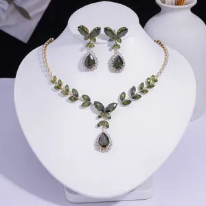 Détail du set de collier et boucles d'oreilles papillon en zircon vert olive sur buste