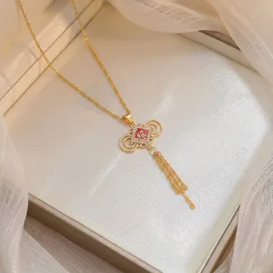 Gros plan d'un collier doré élégant avec pendentif Fu rouge, zircons et détails de glands