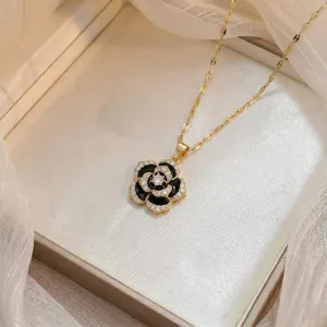 Detailopname van een elegante kamelie hanger ketting met zwart emaille en kristallen