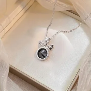 Vue détaillée du collier papillon argenté avec zircone noire facettée dans sa boîte cadeau