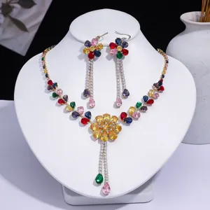 Parure collier et boucles d'oreilles en zircon coloré en forme de fleur sur buste blanc.