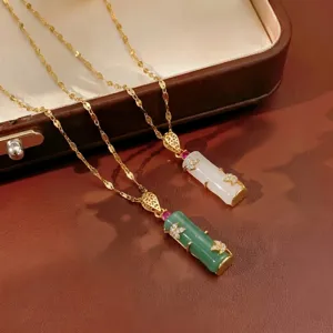 Detail view of green and white jade chalcedony bamboo-shaped pendants on gold chains