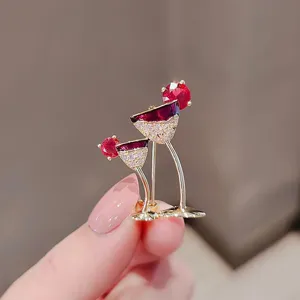 Close-up of elegant gold wine glass brooch with sparkling red gemstones and crystals