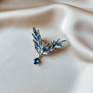 Close-up of elegant blue crystal insect wing brooch on champagne satin fabric background