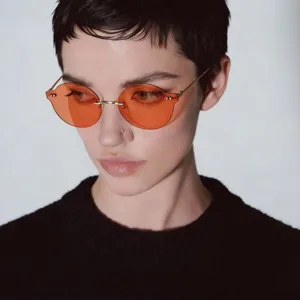 Model wearing retro rimless orange round sunglasses with stylish gold metal temples