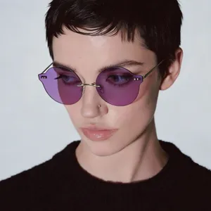 A stylish close-up showing a model wearing retro Y2K purple rimless round sunglasses.