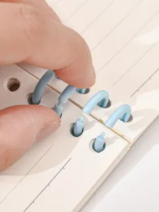 Detailansicht hellblaue Kunststoff segmentierte Ringbucheinlagen auf linierten Notizbuchseiten.