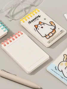 Primer plano detallado de un cuaderno de espiral de bolsillo lindo con motivo de gato y líneas.