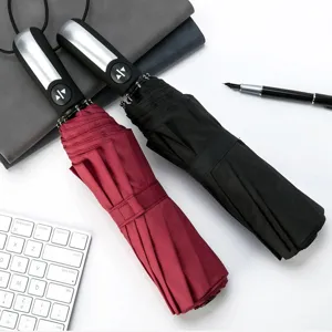 Detailed view of folding automatic umbrellas in red and black, compact business rain and sun shade.