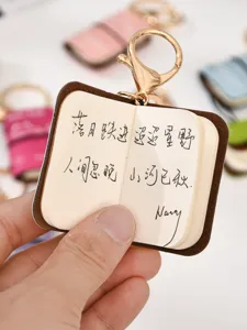 Mini PU leather notebook keychain detail shot, cute portable miniature book bag pendant.
