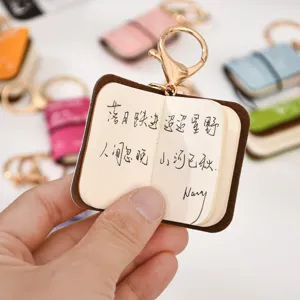 Mini leather notebook keychain with cute poem printed inside, portable and stylish bag pendant.
