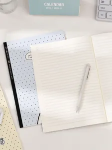 Primo piano del taccuino rigato formato B5 con carta crema, disposizione di cancelleria.