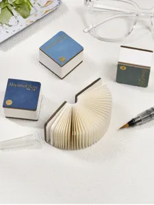 Gedetailleerde close-up van draagbaar zak-akwarelboek met gevouwen pagina's en elegante omslag.