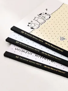 Primo piano della pila di quaderni A5 con gattini, testo del dorso chiaro e pagine puntinate.