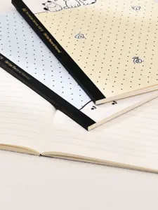 Simpatico taccuino A5 rilegato con design di cartoni animati, copertina puntinata e pagine a righe.