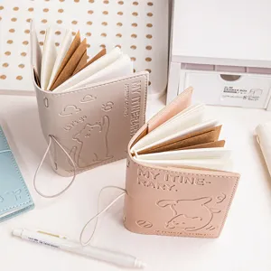 Detailed close-up of two small leather notebooks with embossed cat designs and elastic closures.