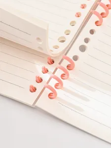 Close-up detail of A5 loose-leaf notebook with pink segmented rings and lined pages.