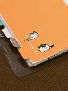 Dettaglio di un taccuino ad anelli arancione con simpatiche illustrazioni di gatti e comode etichette.