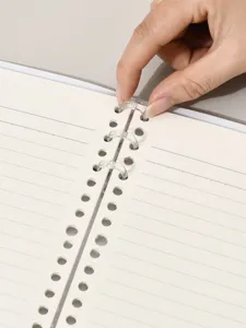 Detailansicht der transparenten Binderringe eines minimalistischen cremefarbenen Notizbuchs