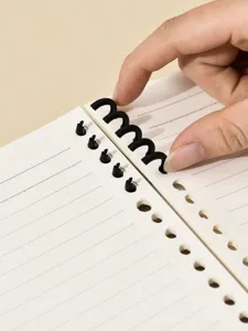Detailgezicht van zwarte afneembare gesegmenteerde ringen op een gelinieerd notitieboek.