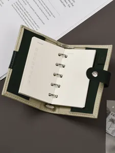 Primo piano dettagliato del mini raccoglitore ad anelli con copertina in pelle verde e sei anelli.