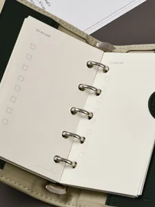 Primo piano dettagliato del taccuino ad anelli aperto con pagine di lista e anelli.